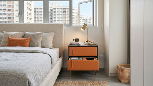 Bedside table with drawers beside an upholstered bed in a modern Singapore HDB bedroom, showing practical closed storage and warm neutral styling.