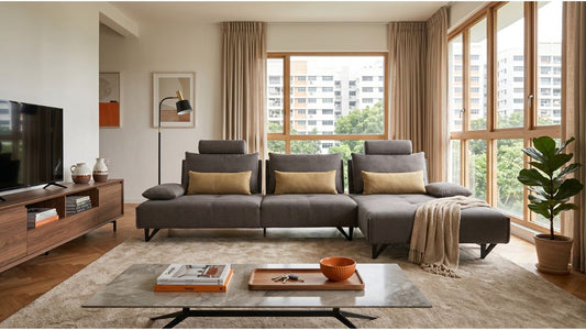 Grey linen fabric sectional sofa with chaise in a bright Singapore living room with wood TV console and natural light