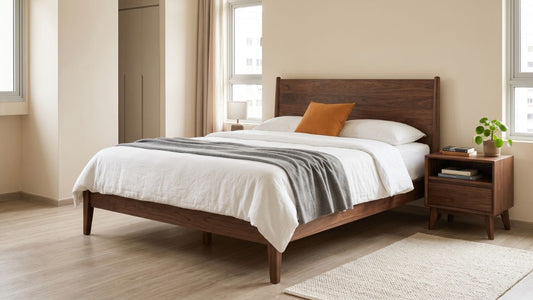 Solid walnut bed frame with dark wood tones in a bright Singapore bedroom with white bedding, warm neutral walls, and matching bedside table.