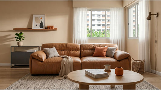 Tan genuine leather sofa in a bright Singapore living room with round coffee table, rug, and soft curtains