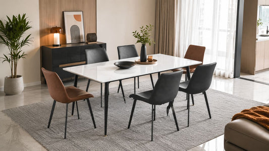 White sintered stone dining table with charcoal and brown chairs in a modern Singapore dining room with warm neutral decor